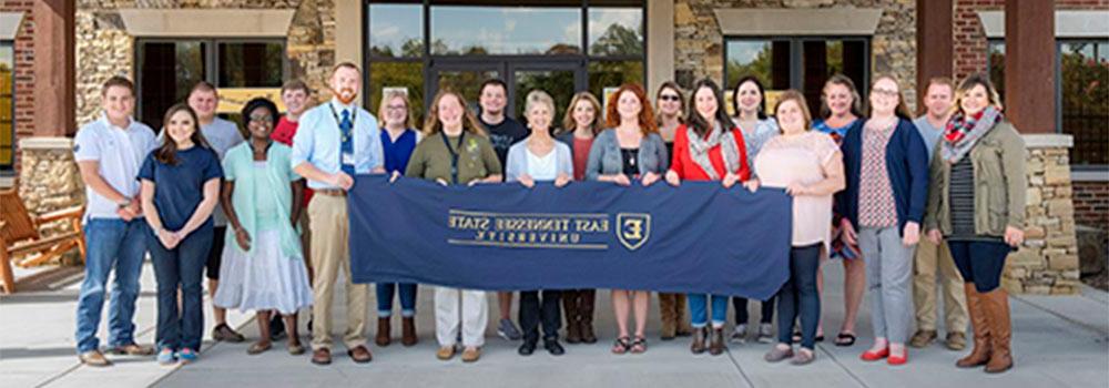 A crowd of people outside our Sevierville campus holding an ETSU banner.